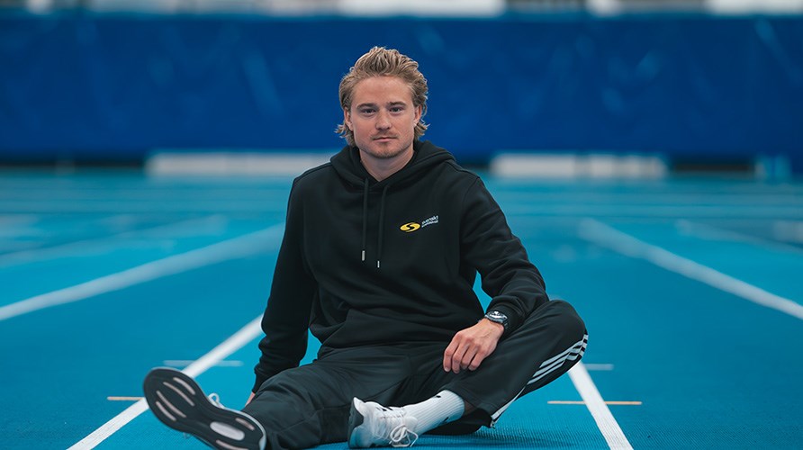 Fredrik sitter p golvet i en friidrottsarena. 